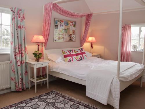 1 dormitorio con 1 cama con dosel y 2 ventanas en Wolvesacre Mill Cottage en Whitchurch
