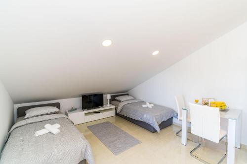 - une chambre avec 2 lits, un bureau et une télévision dans l'établissement Apartments Šmanjak, à Cavtat