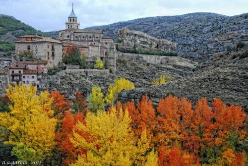 a group of colorful trees in front of a castle at PORTAL DE MOLINA 2 - Piso acogedor en el casco histórico de Albarracín in Albarracín