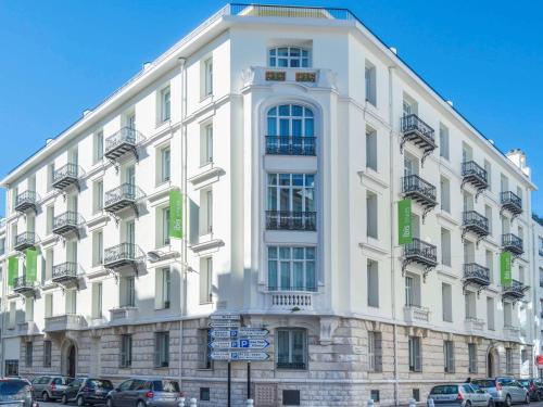 a white building with cars parked in front of it at Ibis Styles Nice Centre Gare in Nice