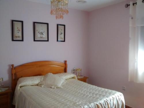 a bedroom with a bed with white sheets and a chandelier at Casa La Huerta in Bubión