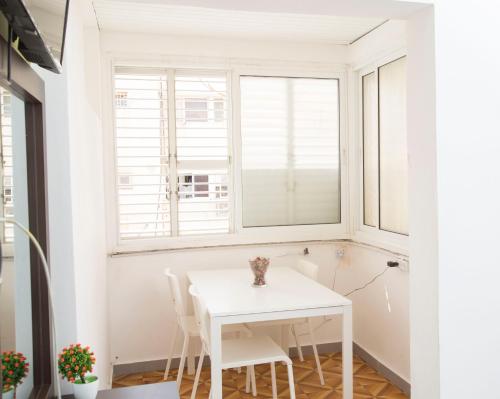 a white table and chairs in a room with a window at Hostel BU93 in Tel Aviv