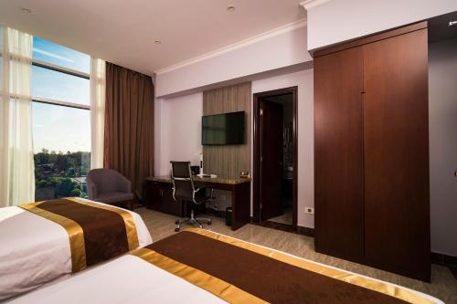 a hotel room with a bed and a desk with a computer at Hotel City Plaza & Suites in David