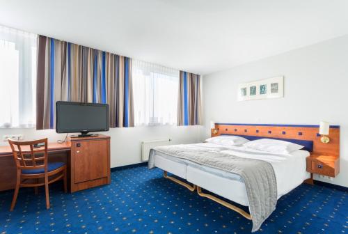 a hotel room with a bed and a desk and a tv at Qubus Hotel Legnica in Legnica