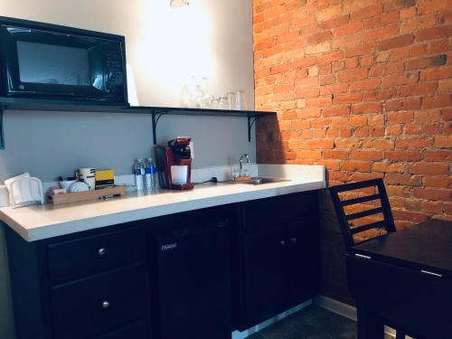 a kitchen with a sink and a brick wall at Lodging at the Gaffer Inn in Corning