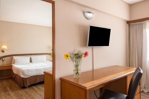 a bedroom with a bed and a table with a vase of flowers at Exe Hotel Colón in Buenos Aires