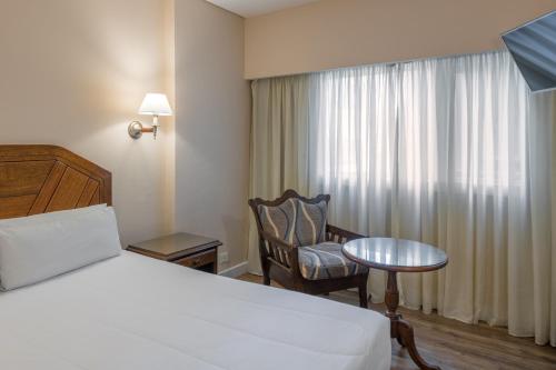 a hotel room with a bed and a chair and a table at Exe Hotel Colón in Buenos Aires