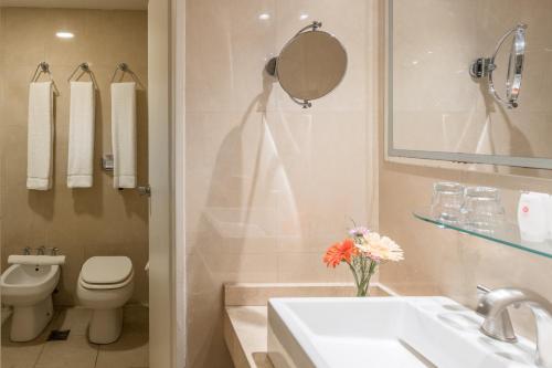 a bathroom with a sink and a toilet and a mirror at Exe Hotel Colón in Buenos Aires