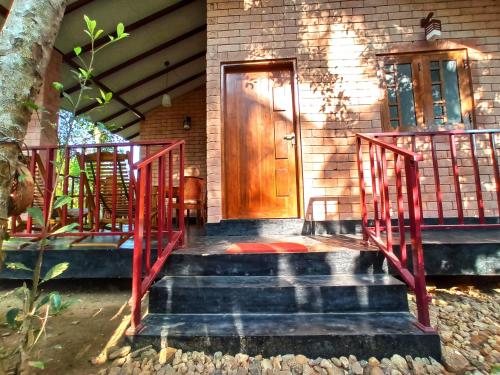 eine Haustür mit rotem Geländer in der Unterkunft Oasis Safari Cottage in Udawalawe