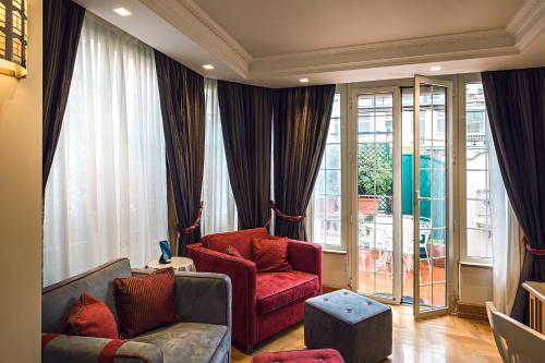 a living room with two red chairs and a window at The Britannia Hotel in Rome
