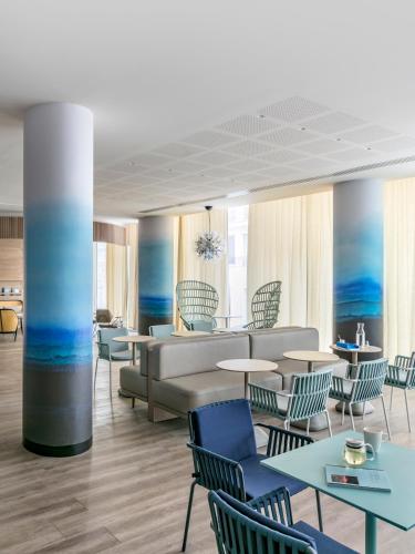 a lobby with a couch and tables and chairs at OKKO Hotels Toulon Centre in Toulon