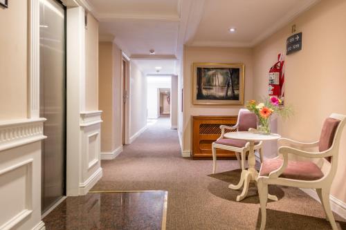 a hallway with a table and two chairs and a vase of flowers at Exe Hotel Colón in Buenos Aires