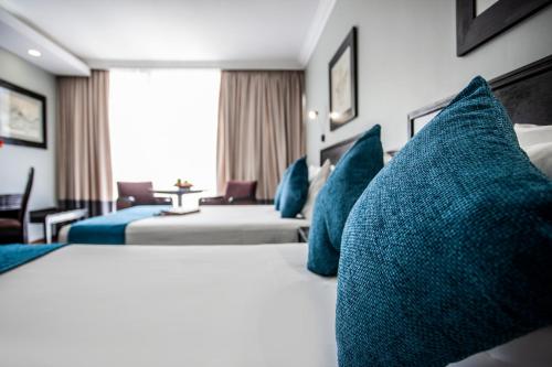 a hotel room with two beds with blue pillows at Avani Maseru Hotel in Maseru