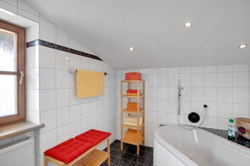 een witte badkamer met een bad en een rode bank bij Ferienwohnung Edelweiß in Schönau am Königssee