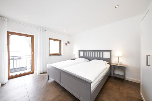 a white bedroom with a large bed and a window at Ferienwohnung Riesling in Lieser