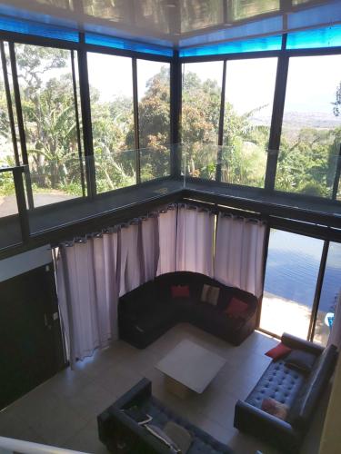 a living room with a couch and large windows at Hotel Monte Campana Heredia in Birrí