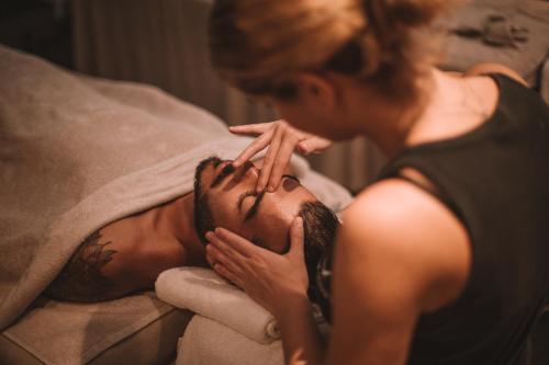 a man laying on a bed next to a woman at Aressana Spa Hotel & Suites - Small Luxury Hotels of the World in Fira