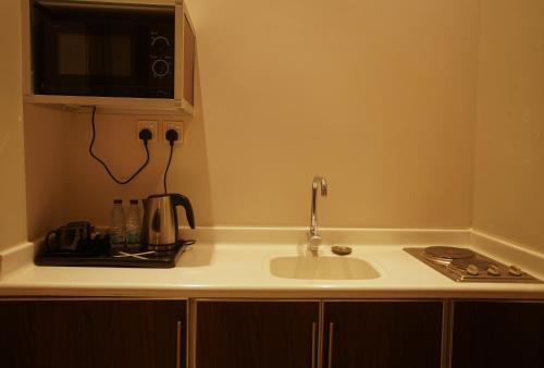 a kitchen counter with a sink and a microwave at Kayan Al Taif Hotel in Taif