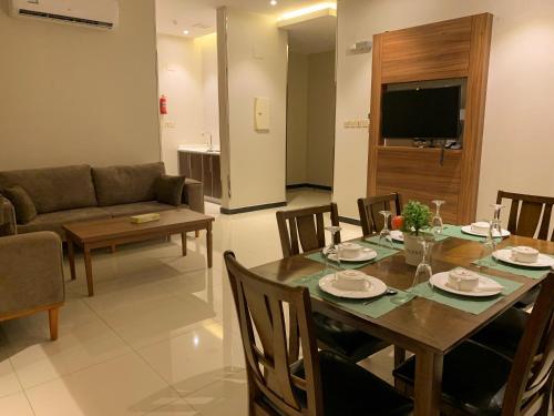 a dining room and living room with a table and chairs at Kayan Al Taif Hotel in Taif
