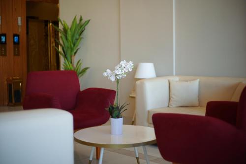 a living room with red chairs and a vase of flowers on a table at Kayan Al Taif Hotel in Taif