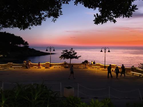 un grupo de personas caminando por la playa al atardecer en Casa Baia Tramonto, en Patù