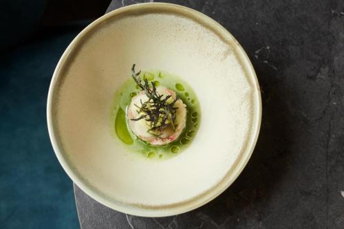 a bowl of food with green peas and meat at Nonam Boutique Hotel Gent in Ghent