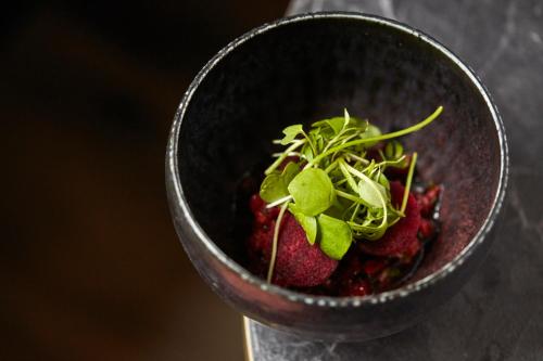a bowl of strawberries with greens on top at Nonam Boutique Hotel Gent in Ghent