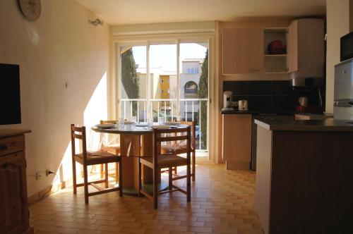 une cuisine avec une table et des chaises et une fenêtre dans l'établissement Lara 4 - T2 spacieux Parking - Près centre-port, île des Loisirs, plage Richelieu, au Cap d'Agde