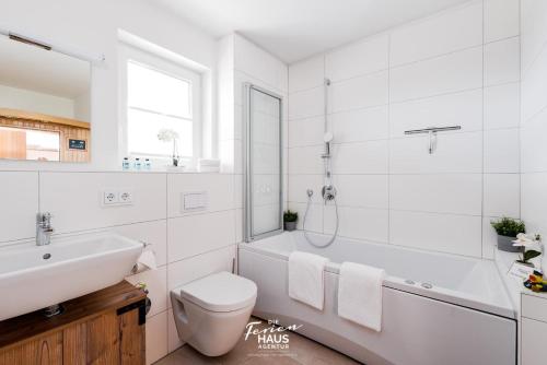 a white bathroom with a toilet and a sink at Ankerhuus in Olpenitz