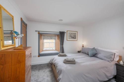 um quarto com uma cama, uma cómoda e uma janela em The Merchants House em Pittenweem