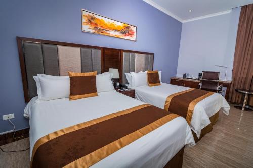 a hotel room with two beds and a desk at Hotel City Plaza & Suites in David