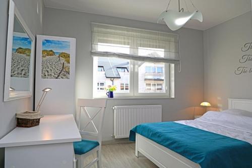 a bedroom with a bed and a desk and a window at Apartament BLUE BAY Darłówko in Darlowko