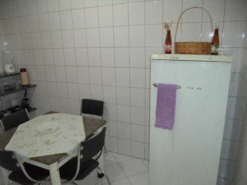a kitchen with a table and a white refrigerator at Jóias Preciosas- Kitnet Mobiliado in Campinas