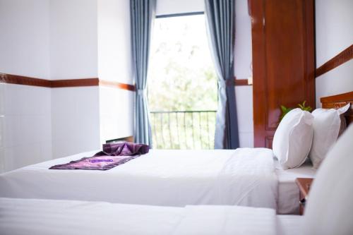 a bedroom with two white beds and a window at Thy Hung legacy hotel in Tuy Hoa