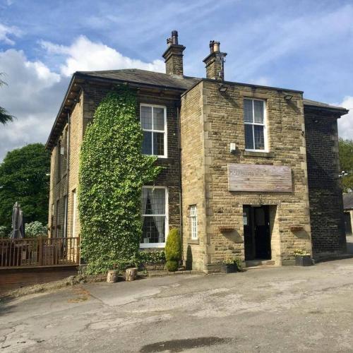 an old brick house with ivy growing on it at Gomersal Lodge Hotel in Cleckheaton