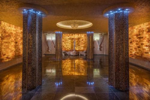 タタにあるホテル クリシュタイ インペリアルの柱のあるロビーとソファが備わる客室です。