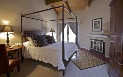 a bedroom with a canopy bed and a fireplace at Merritt House Hotel in Monterey