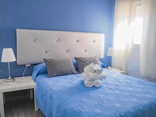 a blue bedroom with a bed with towels on it at ConilPlus apartment SANTA CATALINA III in Conil de la Frontera
