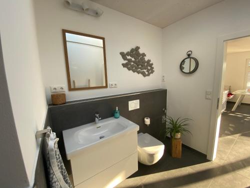 a bathroom with a sink and a toilet and a mirror at Ferienwohnung Vöst in Weil