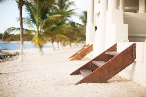 a row of benches on a beach with palm trees at Paamul Hotel in Paamul