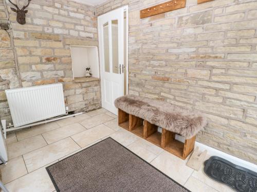 a bathroom with a stone wall and a bench at Wren Cottage in Oldham
