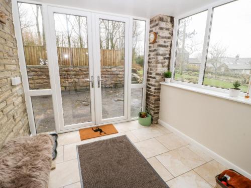 a living room with large windows and a rug at Wren Cottage in Oldham