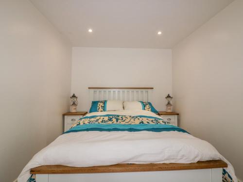 a bedroom with a bed with blue and white pillows at Cove Cottage in Tintagel