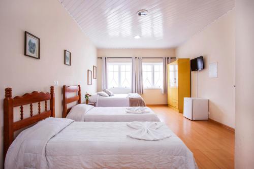 a bedroom with two beds and a television in it at Grand Residences Pousadas in Campos do Jordão