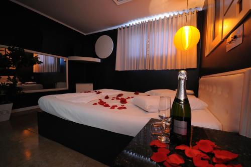 a bedroom with a bed with a bottle of wine and flowers at Motel Paradiso Carazinho (Adults Only) in Caràzinho