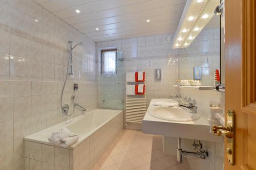 a white bathroom with a tub and a sink at Fürmesli Appartements in Lech am Arlberg
