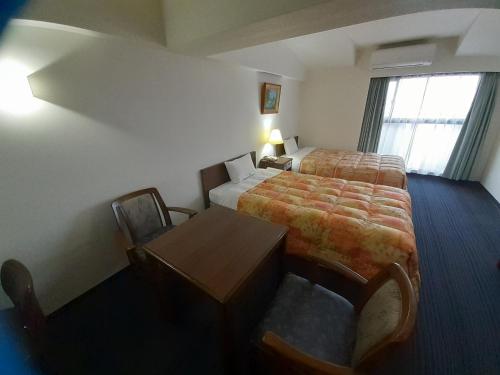 a hotel room with a bed and a desk and a table at Hotel New Plaza Kurume in Kurume