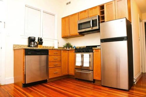 a kitchen with stainless steel appliances and wooden cabinets at Stylish Apartment in Malden. 20 min from Boston in Malden