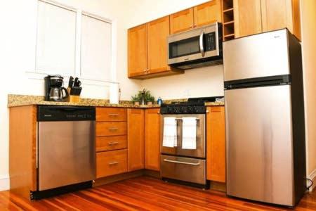 a kitchen with stainless steel appliances and wooden cabinets at Stylish Apartment in Malden. 20 min from Boston in Malden