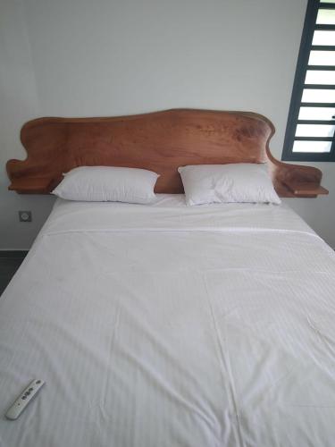 a large white bed with a wooden headboard and pillows at villa Lorenza in Petit-Bourg